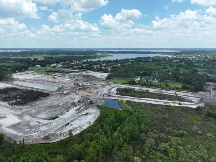 An aerial view of site development construction with heavy machinery, cleared land, and new infrastructure in progress, showcasing modern development and land preparation.