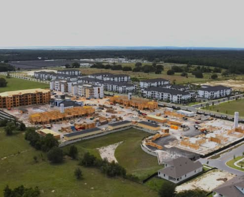 Multi-story apartment complex under construction in a residential neighborhood, showcasing site development and urban planning with ongoing building projects.