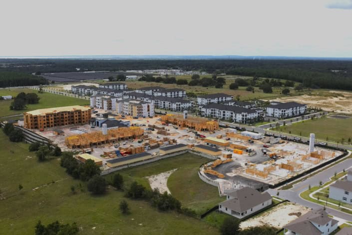 Multi-story apartment complex under construction in a residential neighborhood, showcasing site development and urban planning with ongoing building projects.