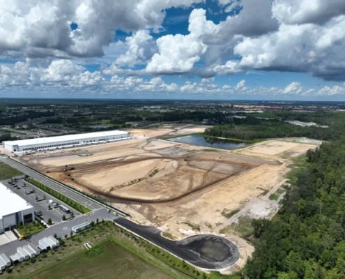 Modern industrial site development with construction in progress, including cleared land, water features, and infrastructure for commercial or industrial facilities.