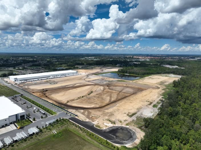 Modern industrial site development with construction in progress, including cleared land, water features, and infrastructure for commercial or industrial facilities.