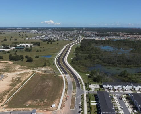 Modern urban development and road construction on a site with water features and residential buildings in Florida.