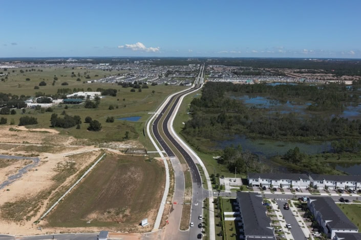 Modern urban development and road construction on a site with water features and residential buildings in Florida.