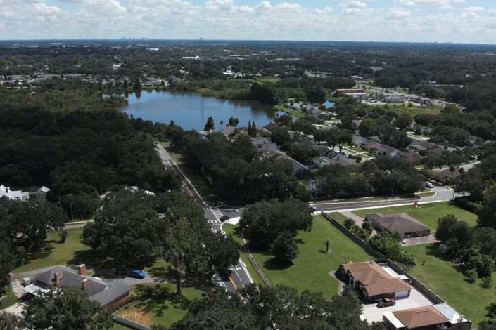 Aerial view of suburban neighborhood with trees, lakes, and residential homes, showcasing site development and community planning in Florida.