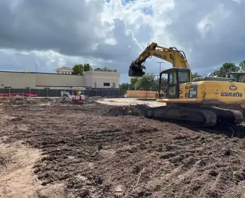 Excavator preparing land for construction at a commercial site.