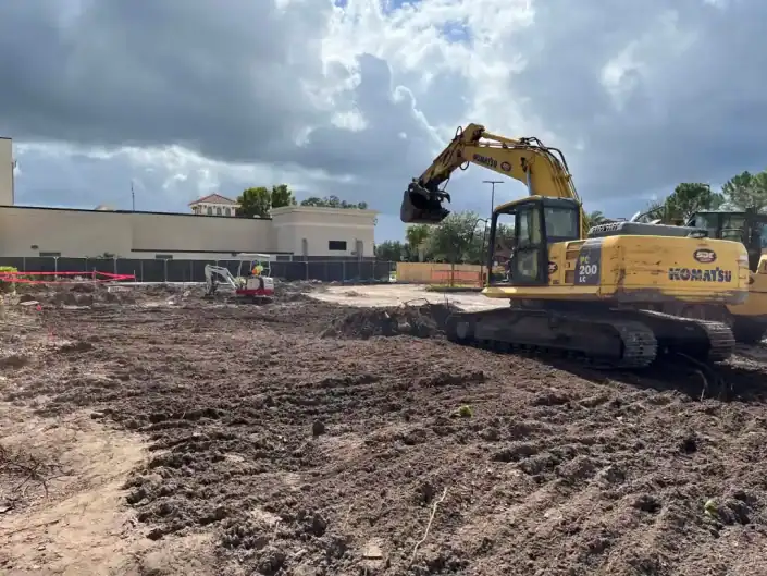 Excavator preparing land for construction at a commercial site.