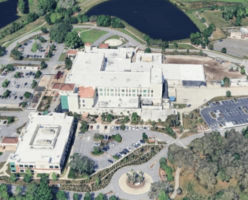 Modern site development and construction project at a large educational facility with parking, landscaping, and surrounding greenery.