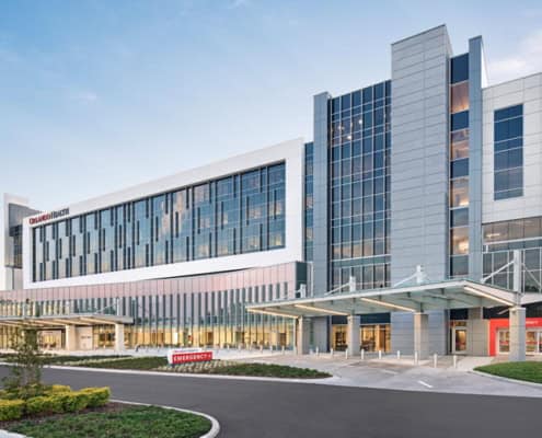 Modern hospital exterior with clinical glass facade and emergency entrance, showcasing advanced healthcare facility architecture for site development projects.