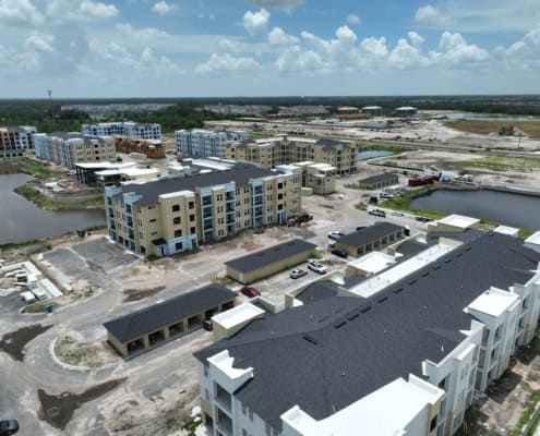 Modern apartment complex under construction with multiple buildings, water features, and construction activity, showcasing site development for residential living.