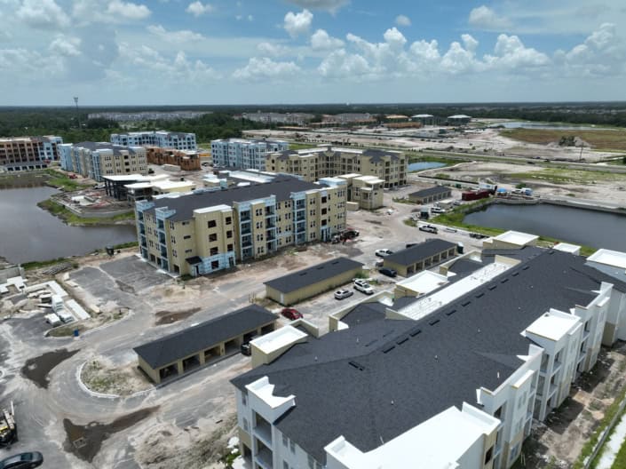 Modern apartment complex under construction with multiple buildings, water features, and construction activity, showcasing site development for residential living.
