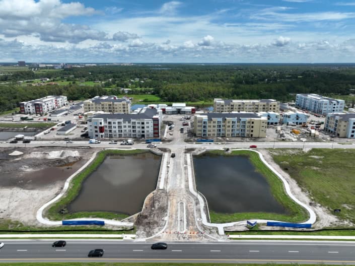 Modern mixed-use construction site with apartment buildings, parking, and water features, showcasing comprehensive site development services for residential communities.