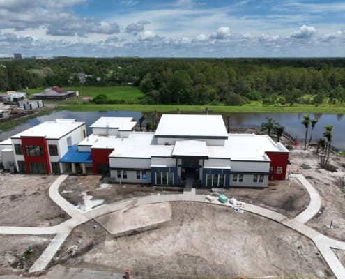 Modern commercial building under construction with innovative design and landscaping, situated by a scenic water body, showcasing expert site development and construction services.