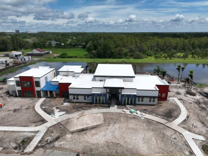 Modern commercial building under construction with innovative design and landscaping, situated by a scenic water body, showcasing expert site development and construction services.