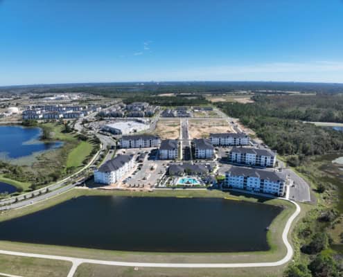 Modern residential community with water features and apartment buildings in a scenic, green landscape, exemplifying innovative site development and urban planning.