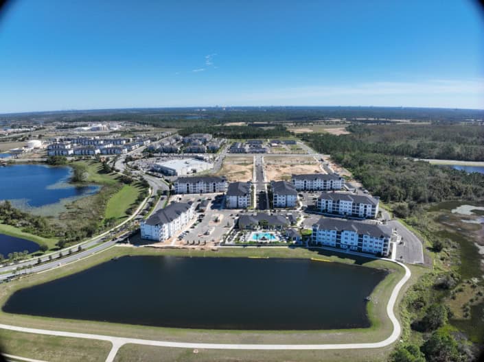 Modern residential community with water features and apartment buildings in a scenic, green landscape, exemplifying innovative site development and urban planning.