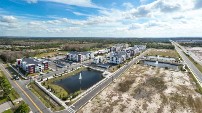 Modern apartment complex with landscaped ponds and fountains in a new residential community, showcasing site development and urban planning excellence for optimal real estate growth.