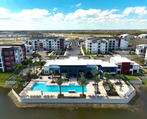 Modern residential apartment complex with pool, waterfront views, and landscaped gardens, perfect for contemporary site development and community living.