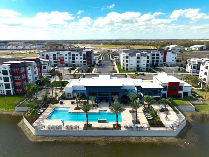 Modern residential apartment complex with pool, waterfront views, and landscaped gardens, perfect for contemporary site development and community living.
