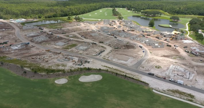 Modern commercial site development with construction progress visible, landscaped golf course, water features, and green spaces, highlighting expert site planning and infrastructure services.
