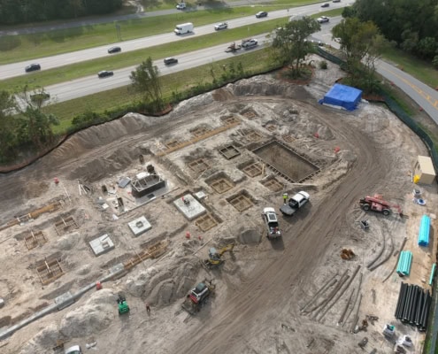Excavation site for road construction, showcasing foundation work, heavy machinery, and construction materials at an urban development project.