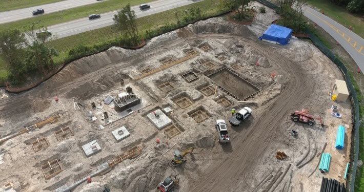Excavation site for road construction, showcasing foundation work, heavy machinery, and construction materials at an urban development project.