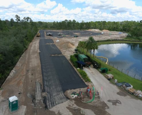 Newly paved roadway construction by SDC Site Development, focusing on commercial infrastructure and landscaping near a pond.