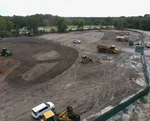 Excavation site for commercial construction development with heavy machinery and earthmoving equipment.