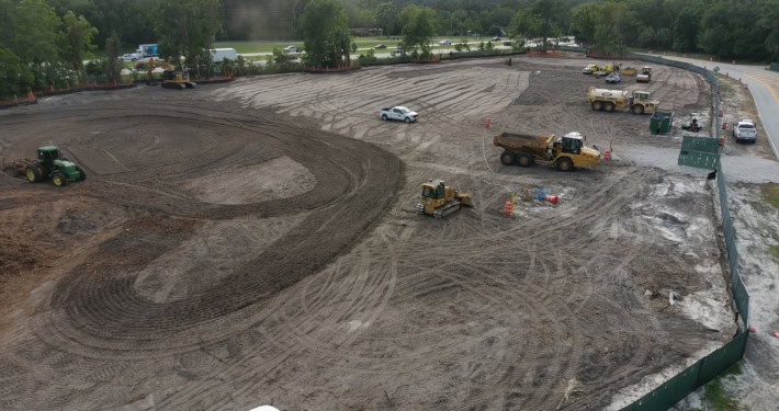 Excavation site for commercial construction development with heavy machinery and earthmoving equipment.