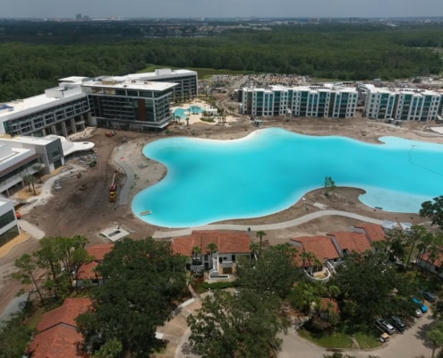 Modern residential community development with luxurious apartment buildings, amenity pools, and ongoing construction.