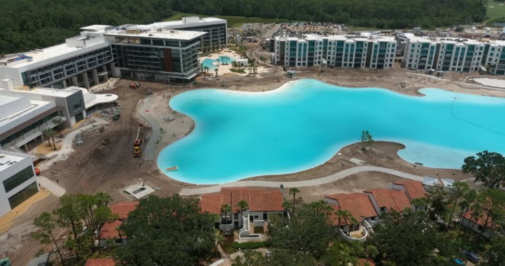 Modern residential community development with luxurious apartment buildings, amenity pools, and ongoing construction.