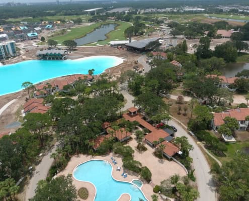 Modern resort pool area with water features, surrounding trees, and outdoor amenities.