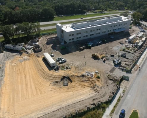 Modern commercial building construction site under development with heavy machinery and construction workers.