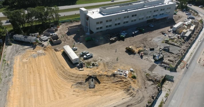 Modern commercial building construction site under development with heavy machinery and construction workers.