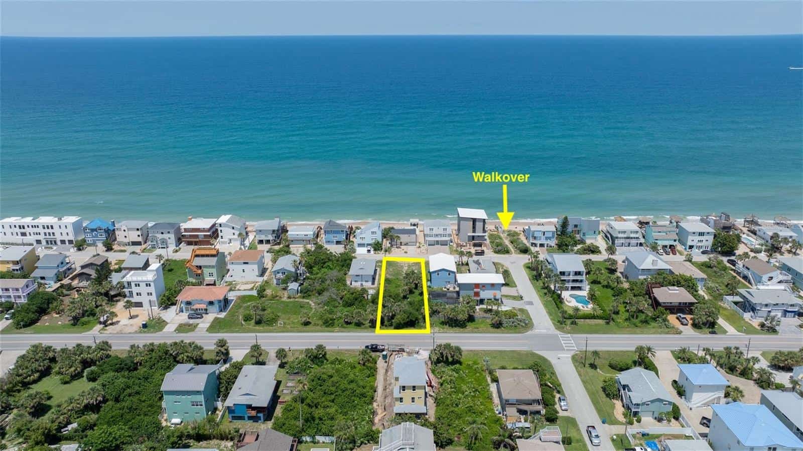 Aerial view of beachfront residential lot with walkover access in a coastal community, ideal for building a custom home near the ocean, featuring nearby amenities and scenic water views.