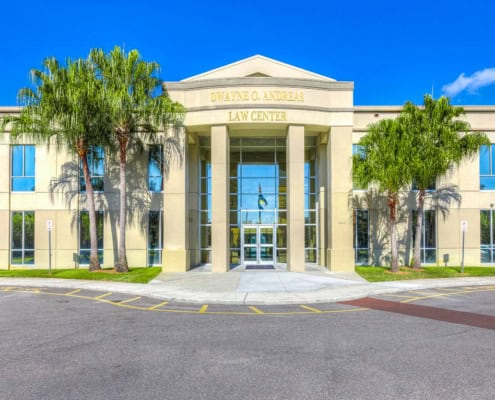 Modern law office building with glass entrance, palm trees, and clear blue sky, showcasing professional legal services and commercial property development.
