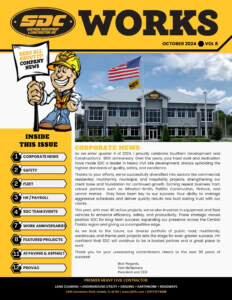 Broad Image of SDC construction company headquarters with American flag and company flags in front, under a blue sky.