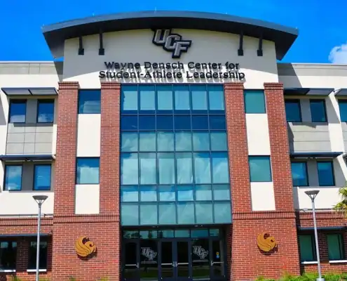 Modern university campus building with UCF logo, showcasing student-athlete leadership center, ideal for site development in higher education infrastructure.
